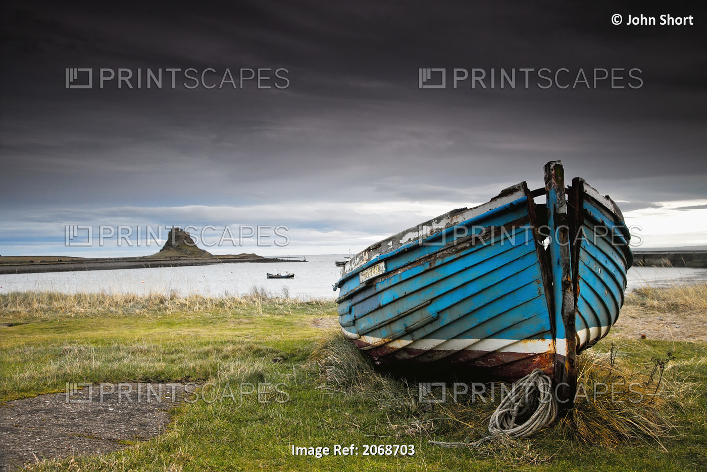 A Weathered Boat Sitting On The Shore With Lindisfarne Castle In The Distance; ...