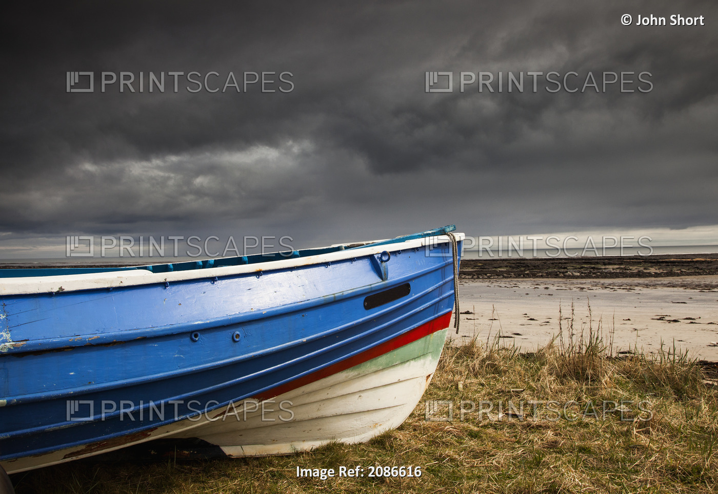 A Colourful Rowboat On The Shore With Dark Storm Clouds Overhead; Boulmer, ...
