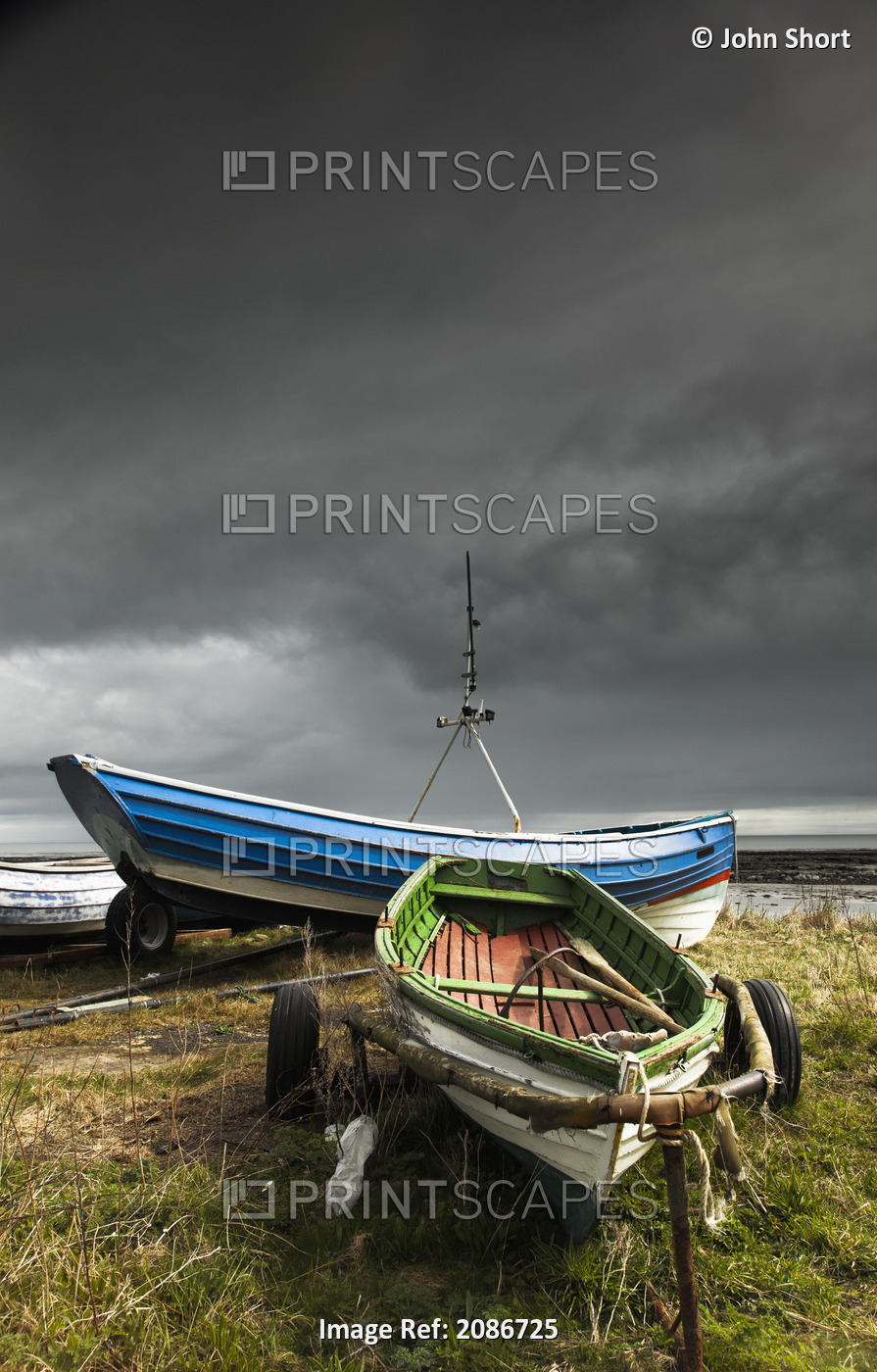 Rowboats sitting on trailers on the shore under storm clouds;Boulmer ...