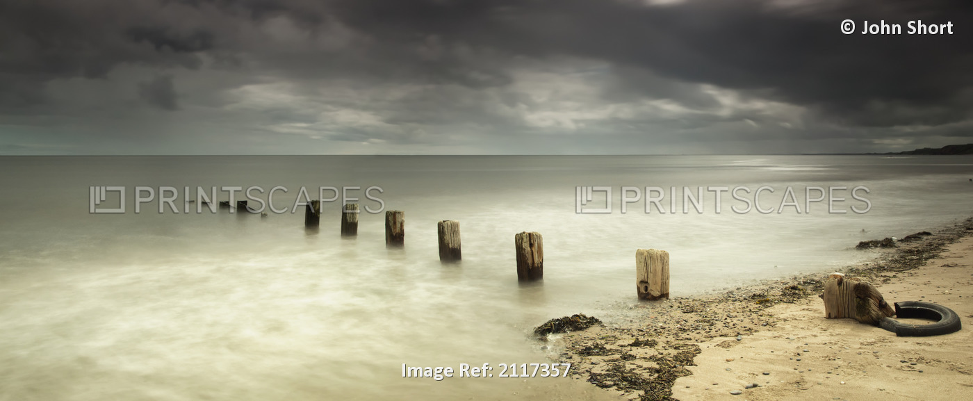 Wooden posts submerged in the water off a beach;Berwick northumberland england